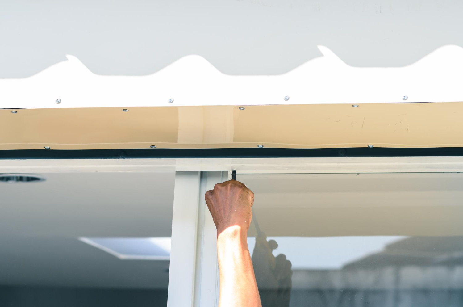 Professionnel en train de réparer un volet roulant coincé à l'aide d'outils